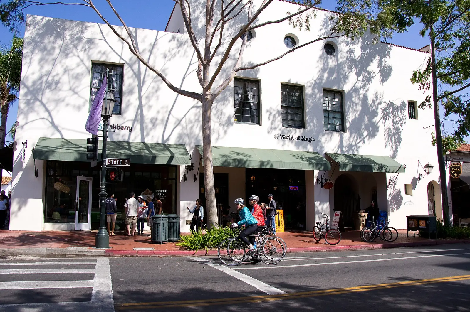 Storefronts and people on bikes along State Street in downtown Santa Barbara
